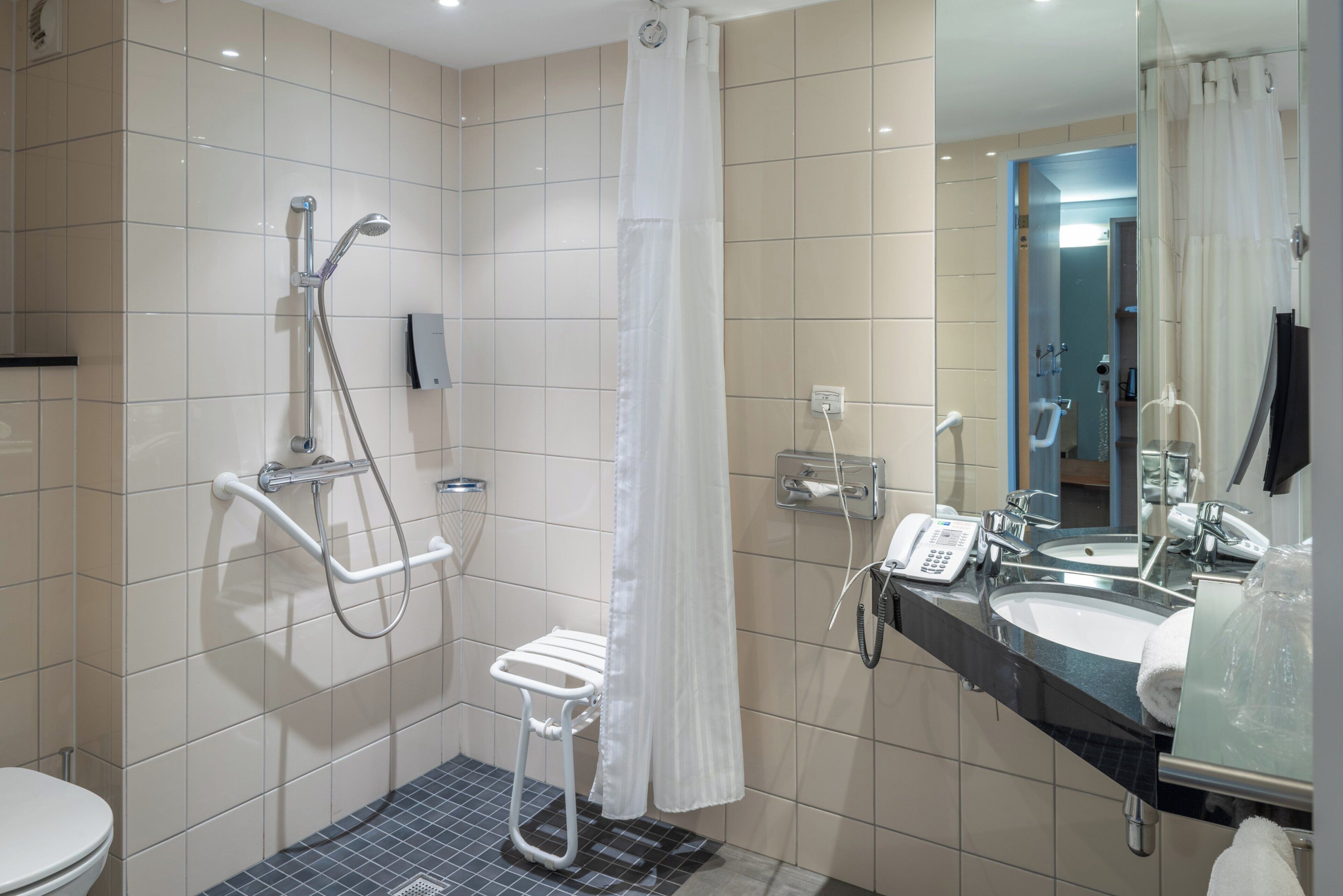 Un baño moderno con ducha, inodoro y lavamanos dobles.