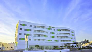 Un hôtel Holiday Inn moderne, avec une façade blanche et des touches de vert, doté d’une entrée couverte et d’un espace de stationnement.