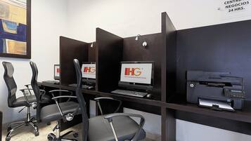 A hotel business center with HP computers, chairs, and a printer.