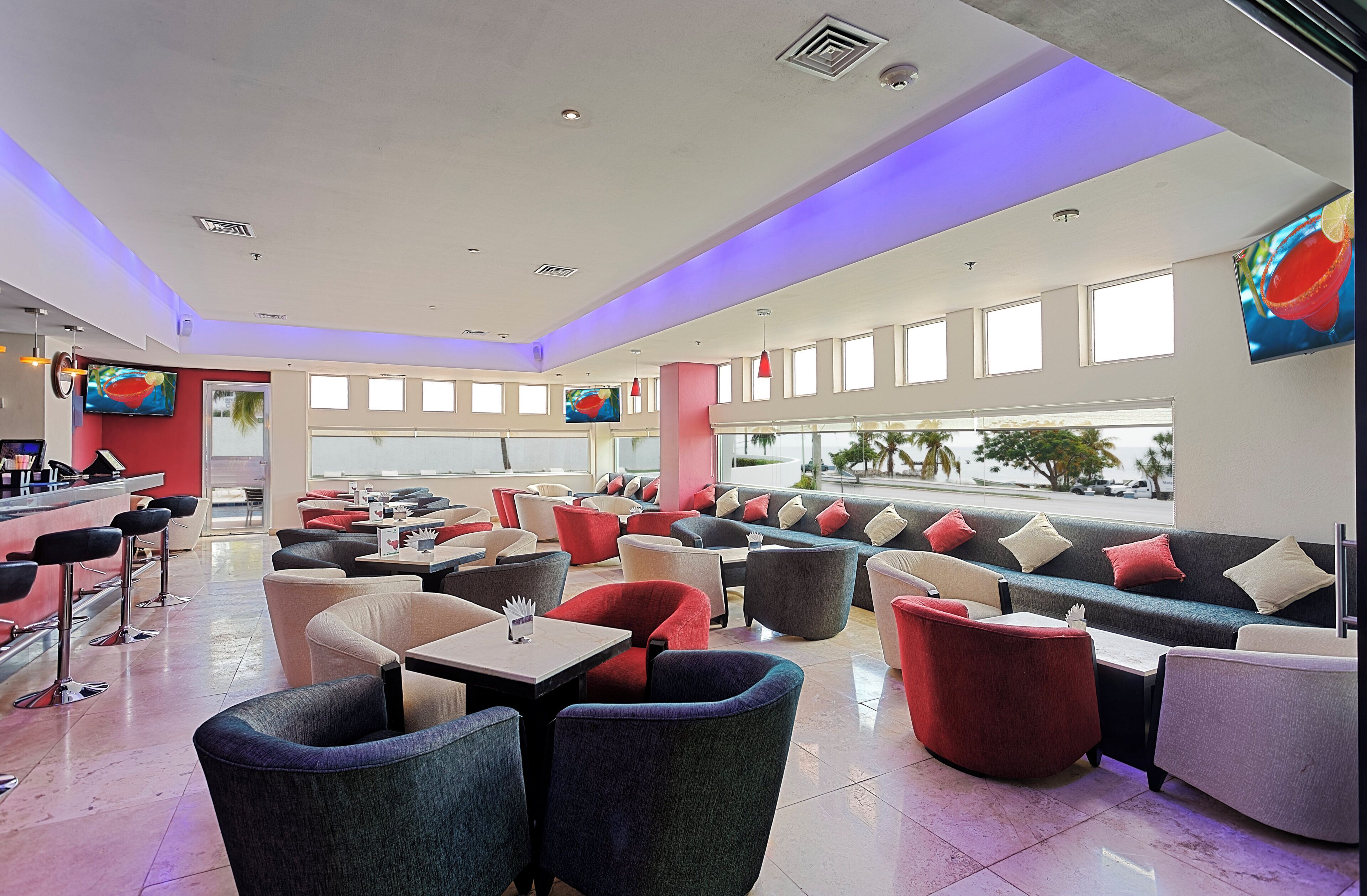 A modern lounge area with multiple seating options, including sofas and chairs, arranged around a central bar area.