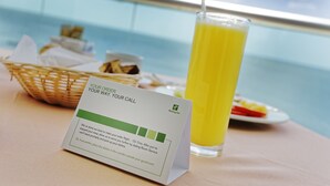 Una mesa con un vaso de jugo de naranja, una cesta de comida y una tarjeta con indicaciones.