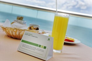 Una mesa con un vaso de jugo de naranja, una cesta de comida y una tarjeta con indicaciones.