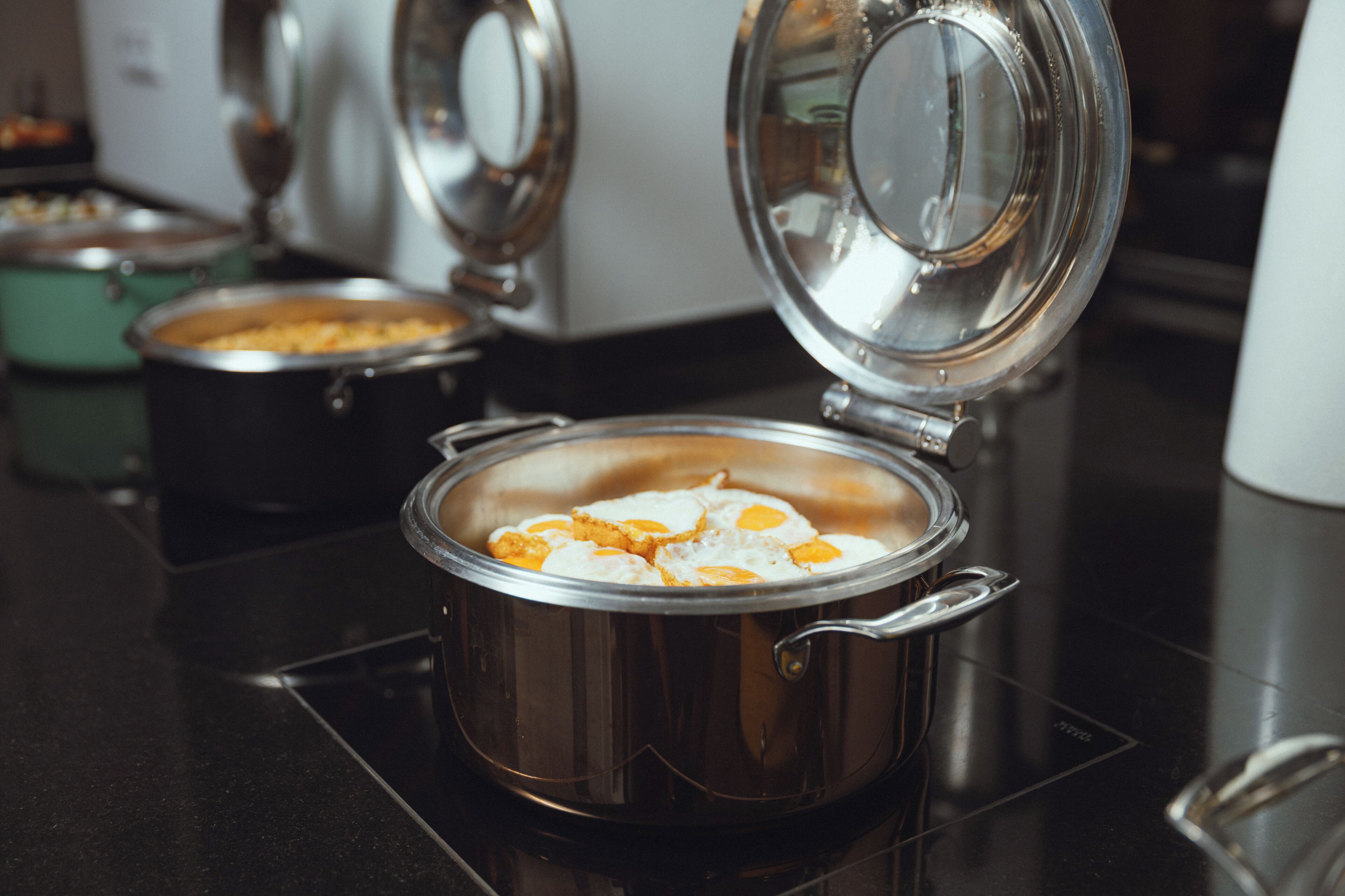 A kitchen with a stovetop, a pot with eggs, and a kettle.