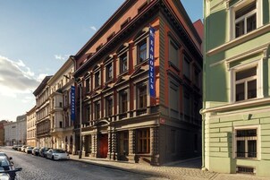 Una fila di edifici storici con un'altra fila di auto parcheggiate davanti.