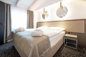 Quarto de hotel com uma cama grande, duas mesas de cabeceira e um espelho na parede.
