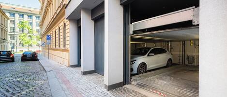 Un edificio con garaje para coches, calle adoquinada y vehículos estacionados.