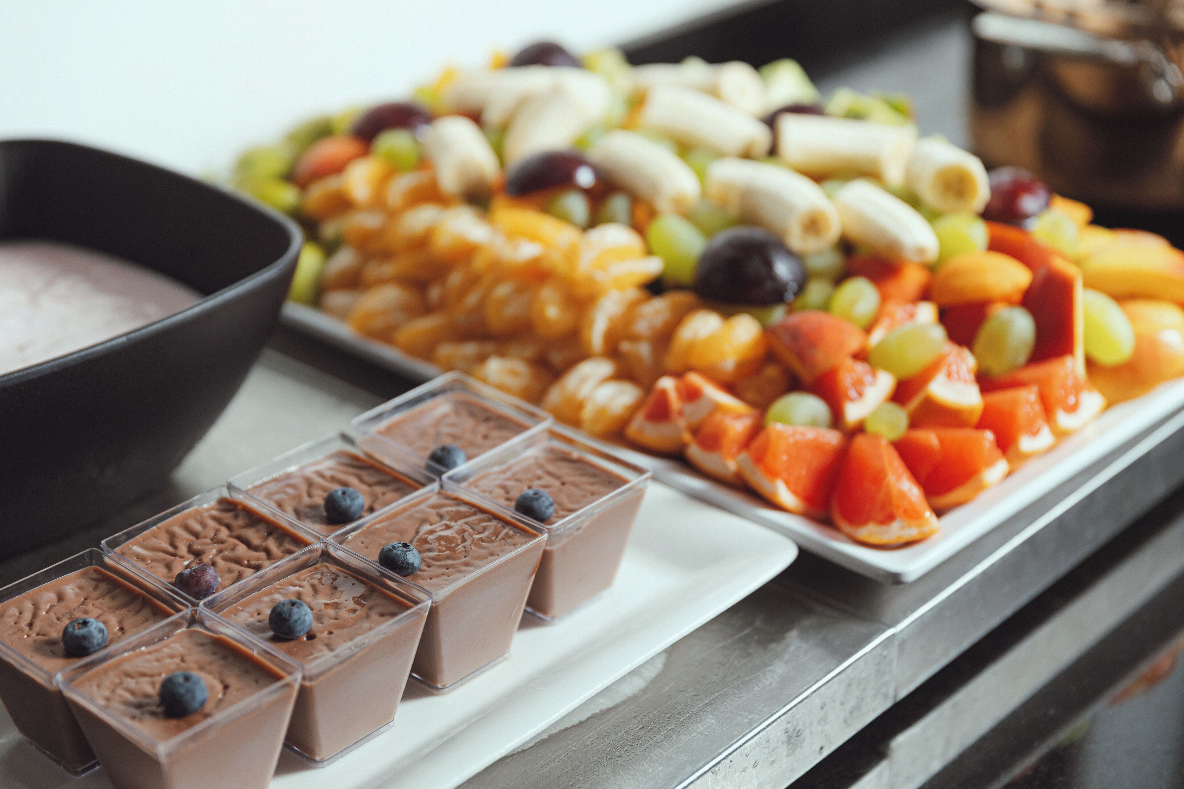 A buffet with various food items including chocolate desserts, fruits, and a bowl of soup.