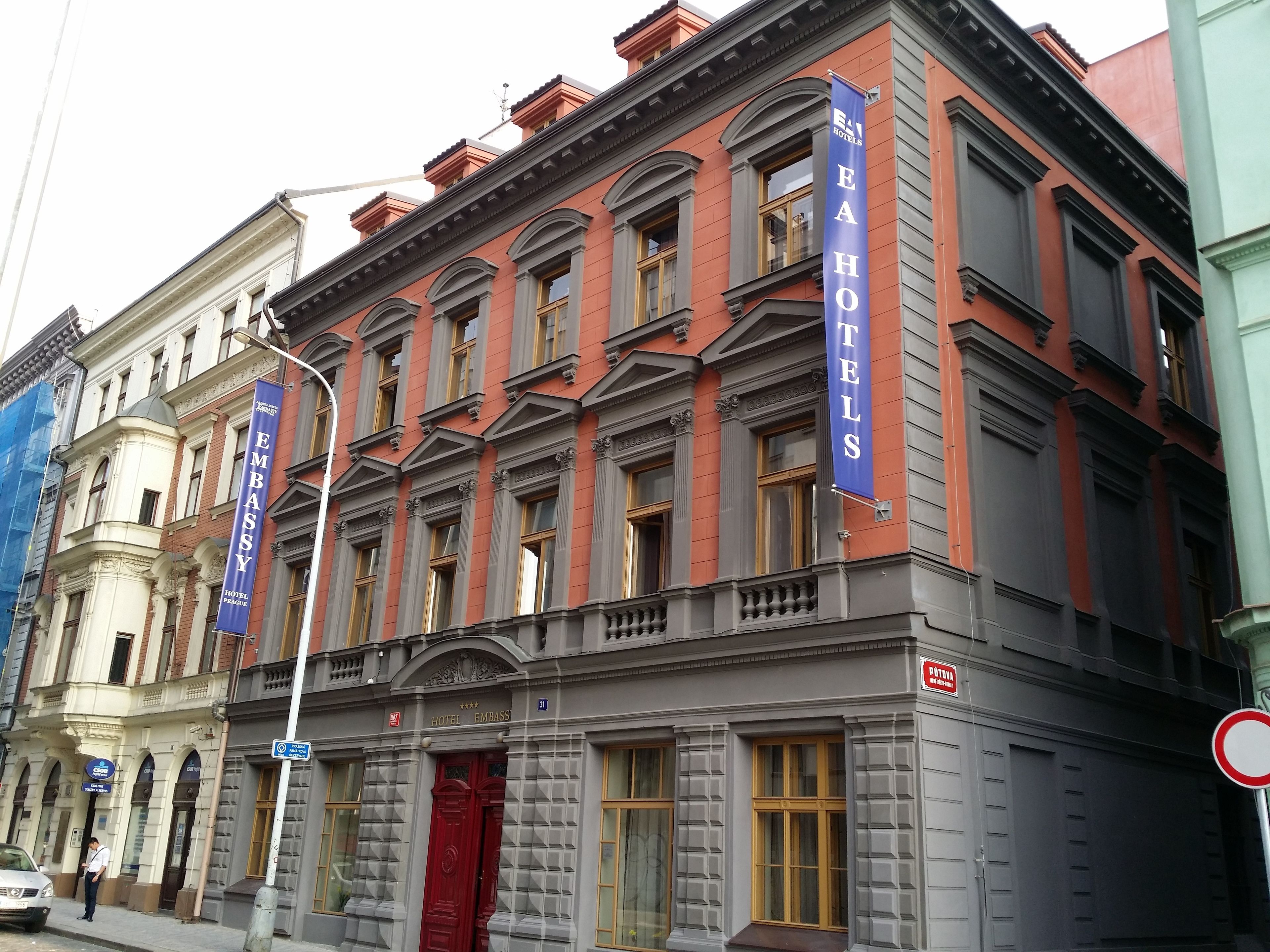 A historic building with a red facade, multiple windows, and a prominent red entrance door.
