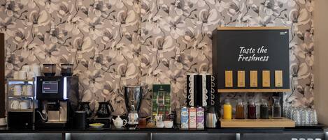 A coffee station with a coffee machine, tea pot, and various drink dispensers.