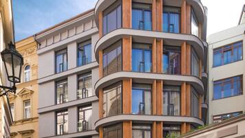 Un edificio moderno de varios pisos con fachada curva, ventanas amplias y una calle adoquinada.