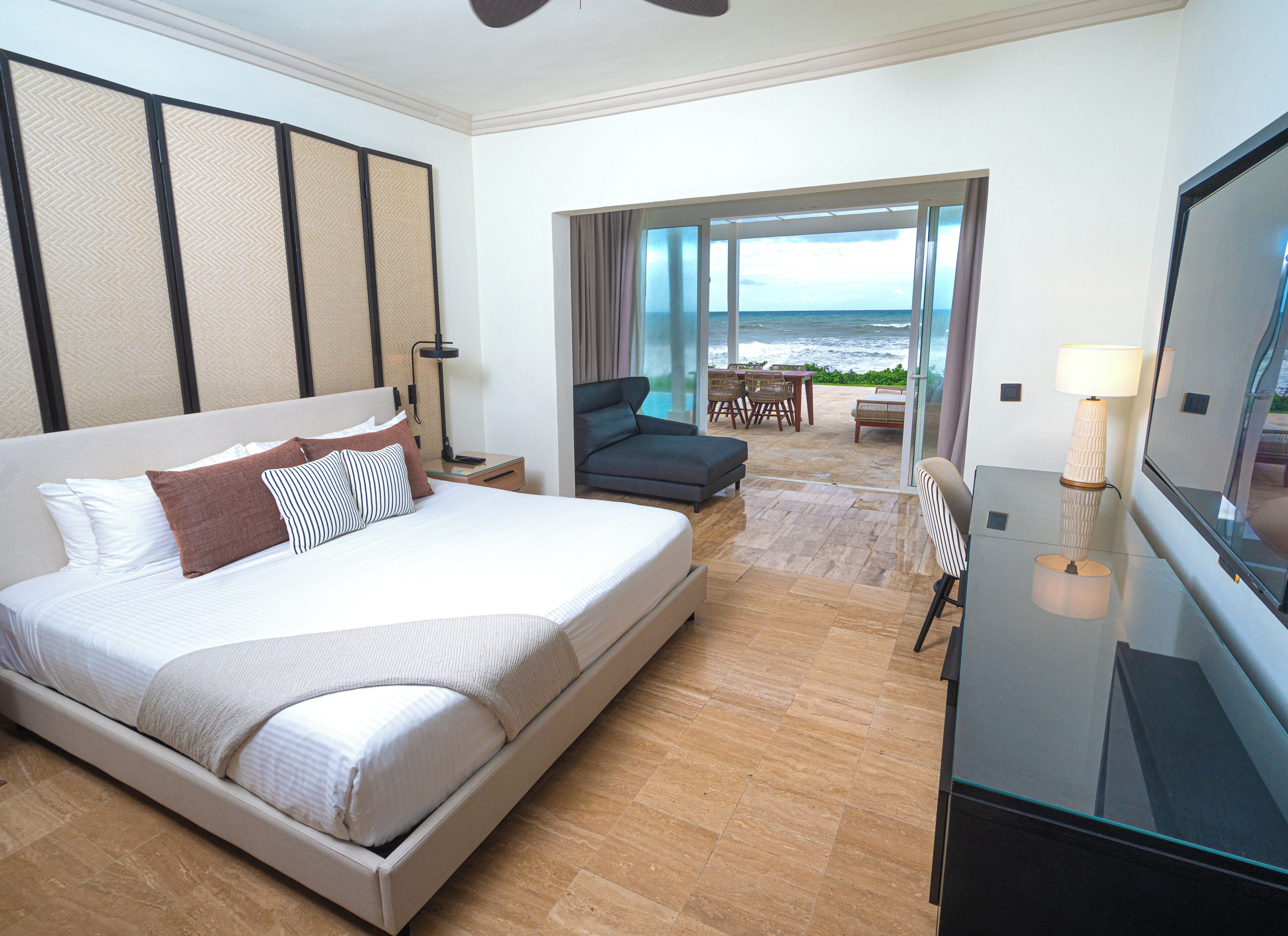 Habitación de hotel con una cama grande, televisión, escritorio y vista al océano.