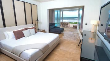 Habitación de hotel con una cama grande, televisión, escritorio y vista al océano.