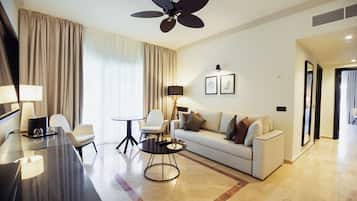 A modern hotel room with a large ceiling fan, a sofa, a dining table, and a lamp.