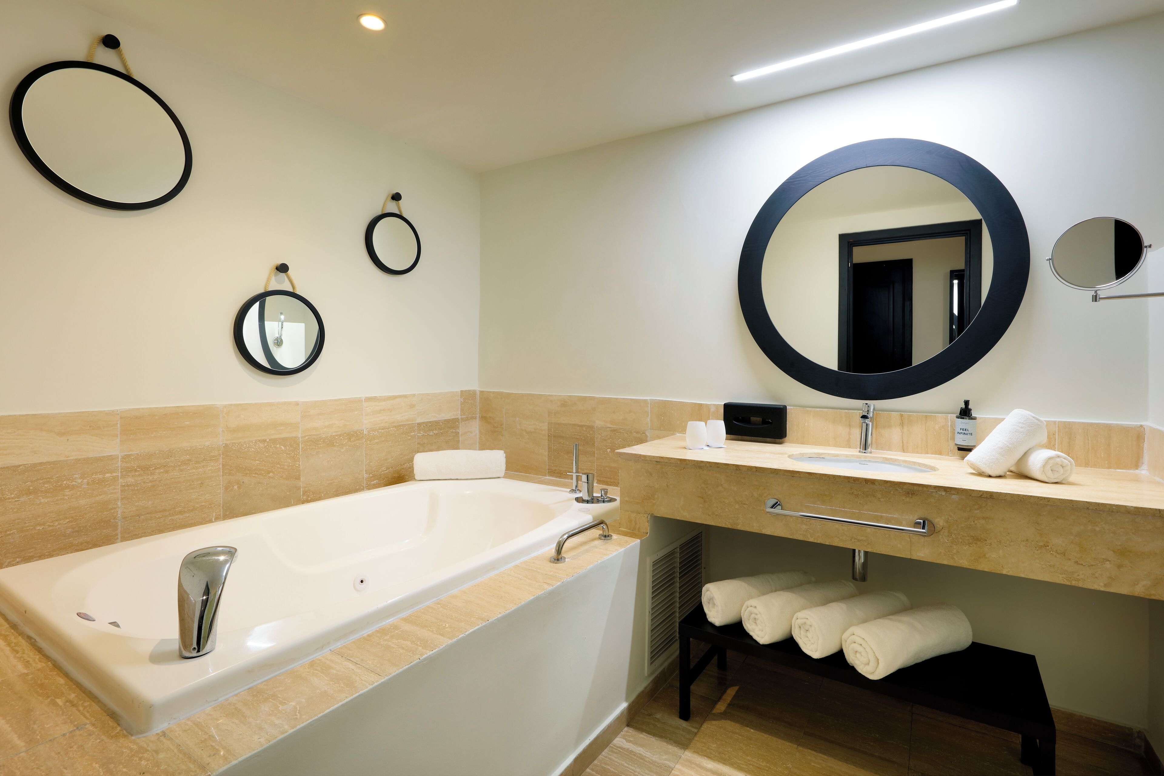 Une salle de bain moderne avec une grande baignoire, un meuble-lavabo avec un miroir et des serviettes soigneusement pliées.