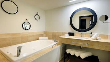 Une salle de bain moderne avec une grande baignoire, un meuble-lavabo avec un miroir et des serviettes soigneusement pliées.