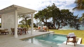 Un espace piscine agrémenté d’une pergola, de mobilier d’extérieur et offrant une vue sur l’océan.