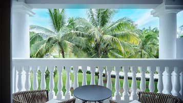 A balcony with white balustrades, two wicker chairs, and a round table.