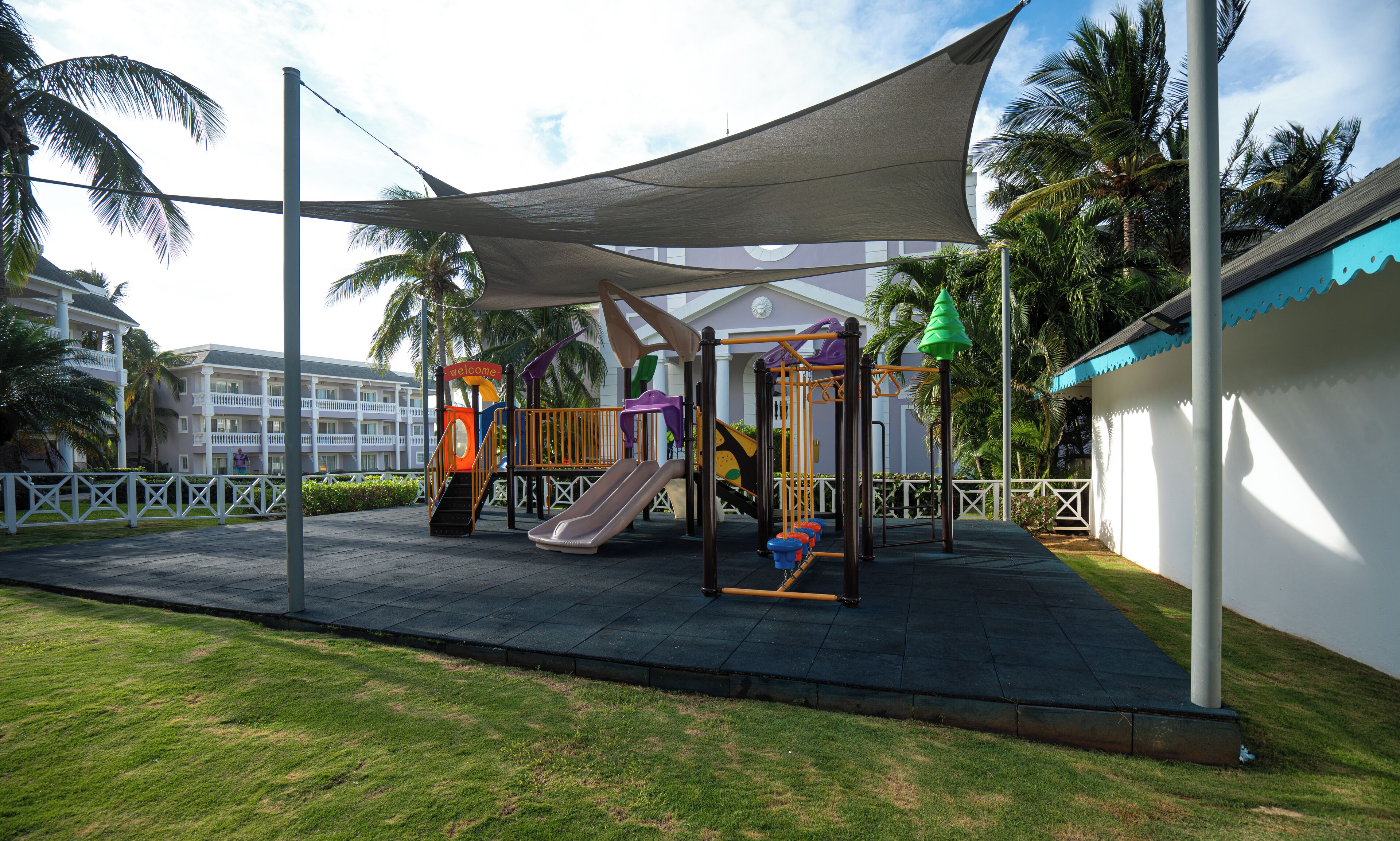 A playground with a slide, climbing structures, and a shaded area.