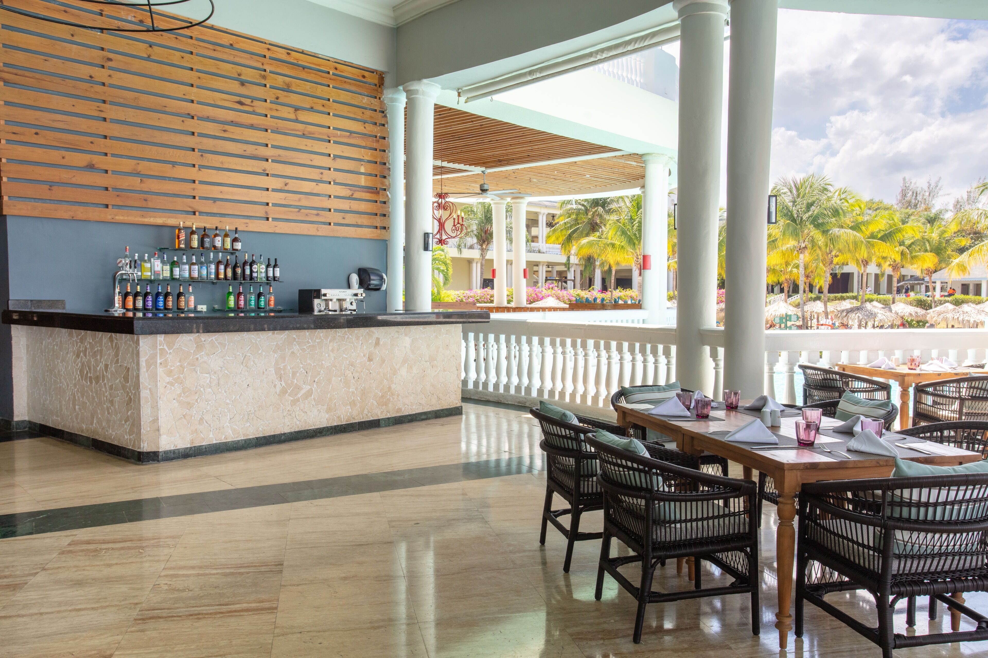 Vestíbulo de hotel con zona de bar, asientos y vistas al exterior.
