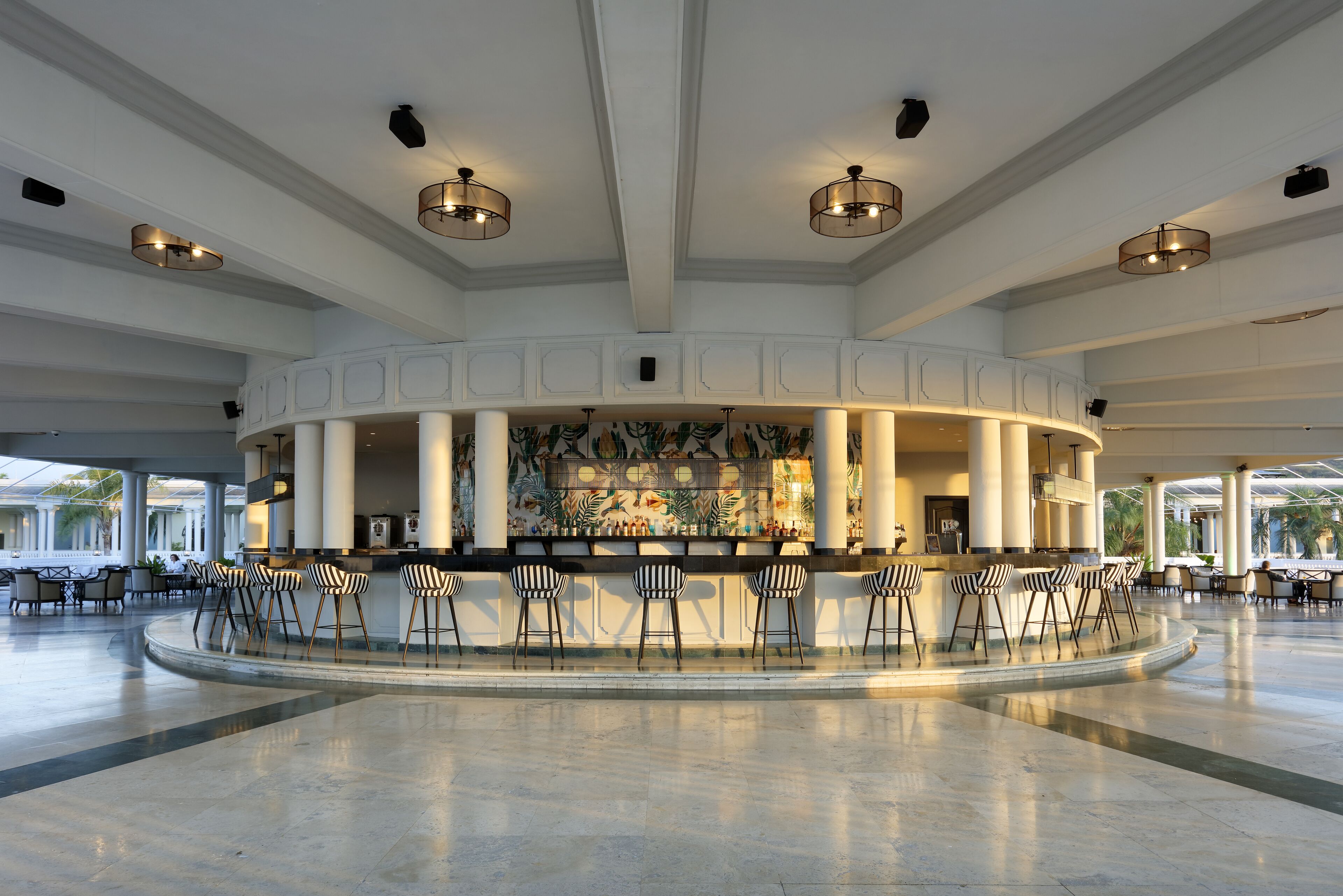 Un bar espacioso con distribución curva, diversas opciones de asiento y un mural decorativo.