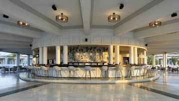 Un bar espacioso con distribución curva, diversas opciones de asiento y un mural decorativo.