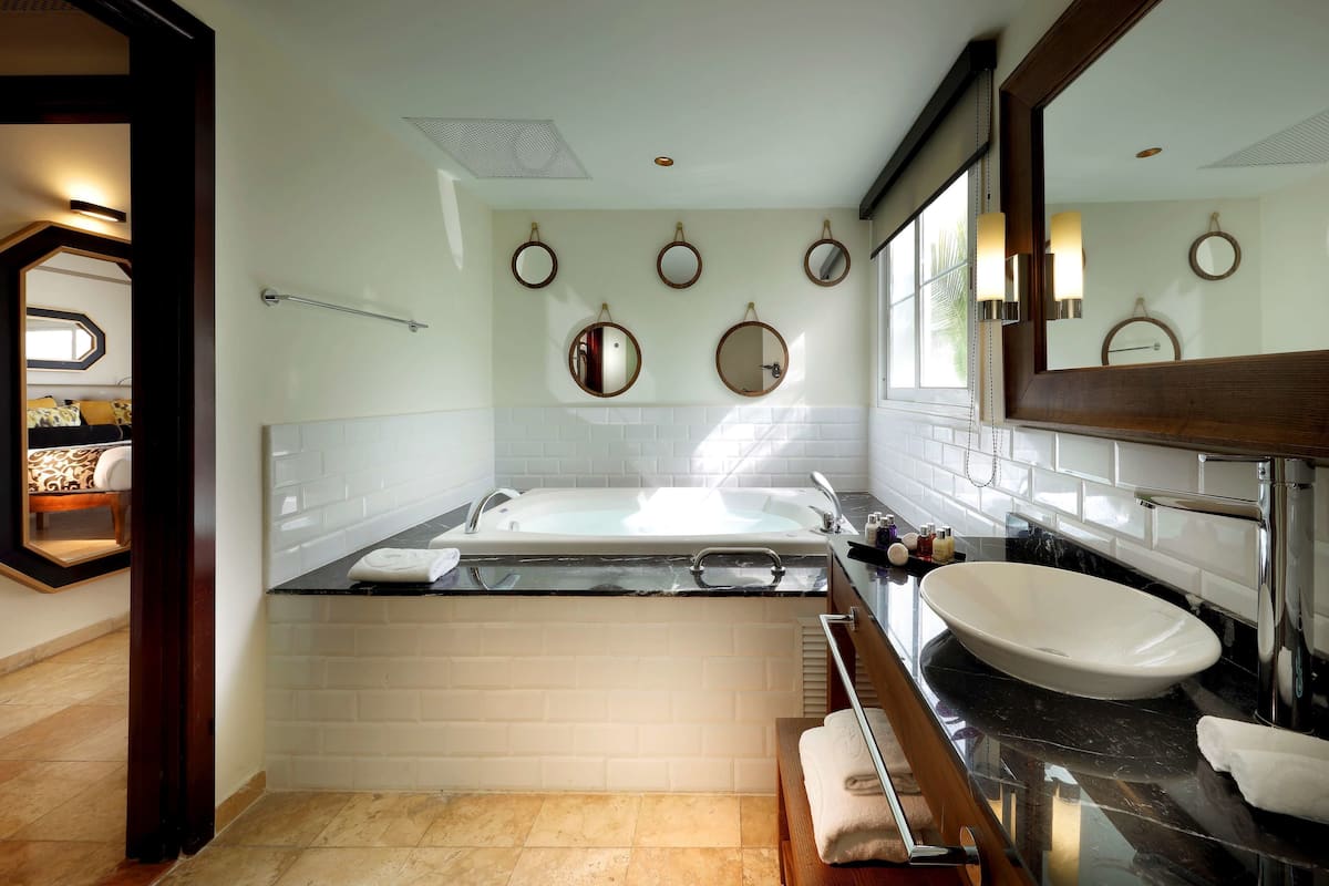 A modern bathroom with a bathtub, a large mirror, and a vanity with a sink.