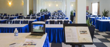 A conference room with tables set up for a meeting, laptops, water bottles, and informational brochures.