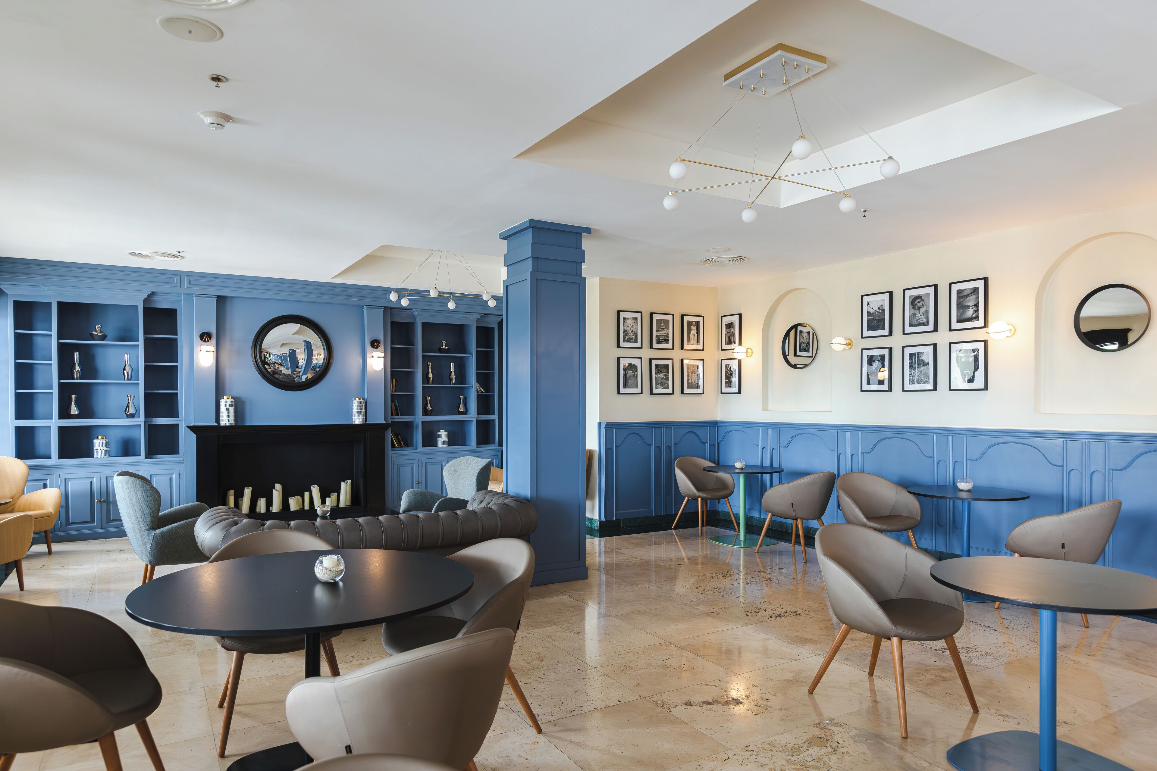 A modern lounge area with blue walls, a fireplace, and a variety of seating options including sofas and chairs.