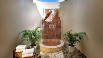 Shower area features a circular basin and a wooden bench with towels.