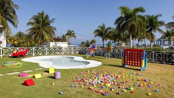 Zona de piscina con piscina infantil, pelotas de colores y estructuras de juego.