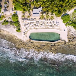 Relax by the large pool surrounded by a sandy beach area and lush greenery.