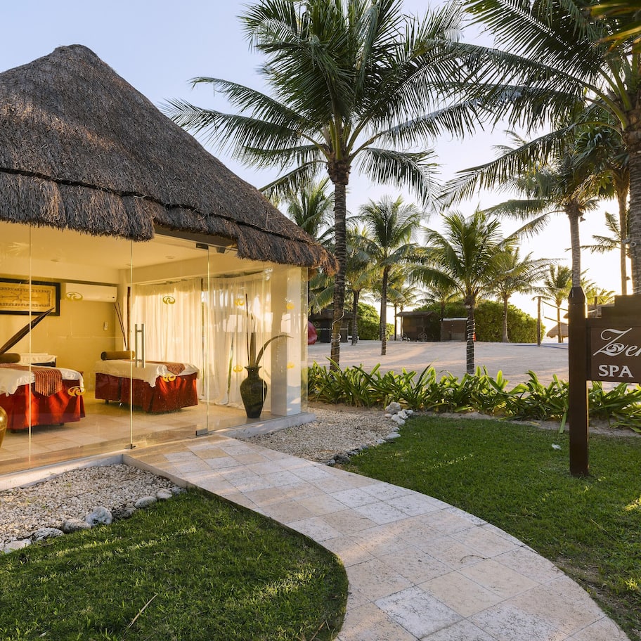 A thatched-roof building with a glass facade, a sign reading "Zentropa SPA," and a pathway leading to the entrance.