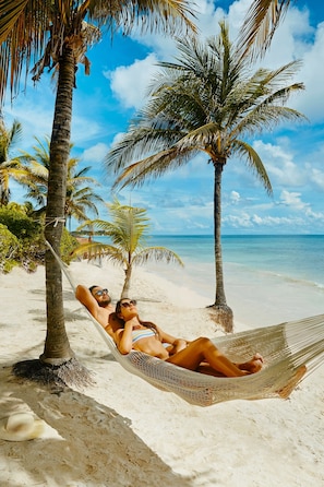 A hammock on a sandy beach with palm trees and a clear blue sky. - TRS Yucatan Hotel - Adults Only - All Inclusive (Kantenah)