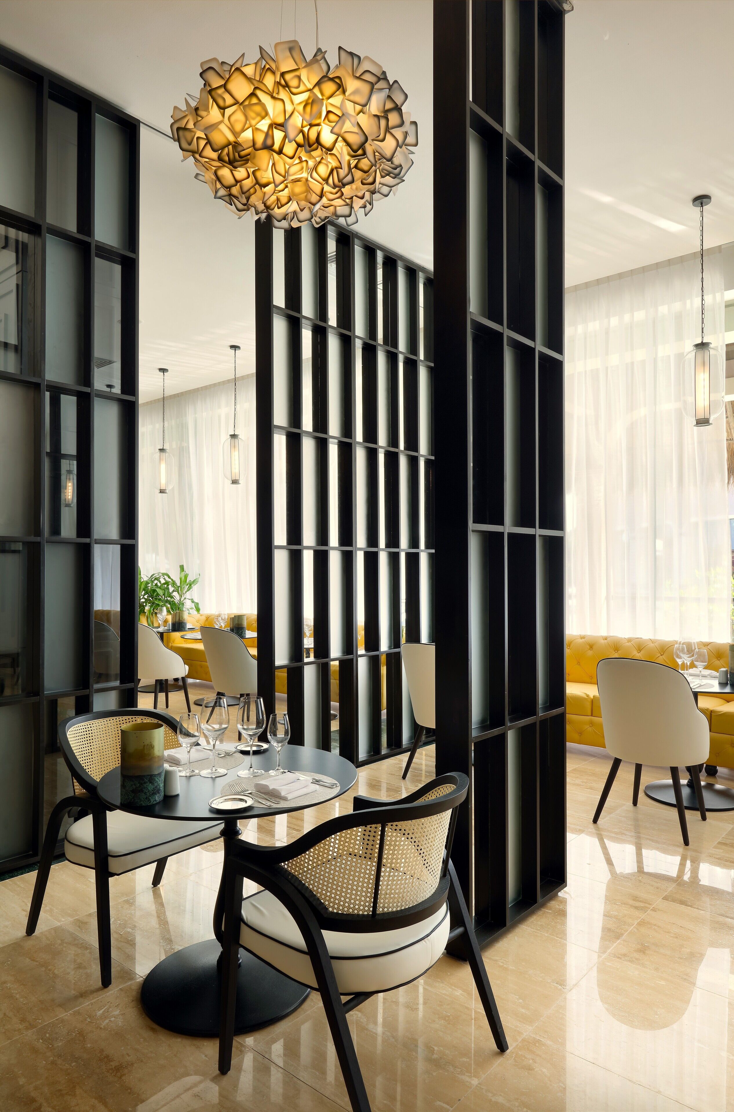 A modern dining area with a round table, black chairs, and a unique pendant light.