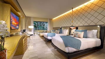 A hotel room with a large bed, a desk, a chair, a TV, and a window with a view of trees.