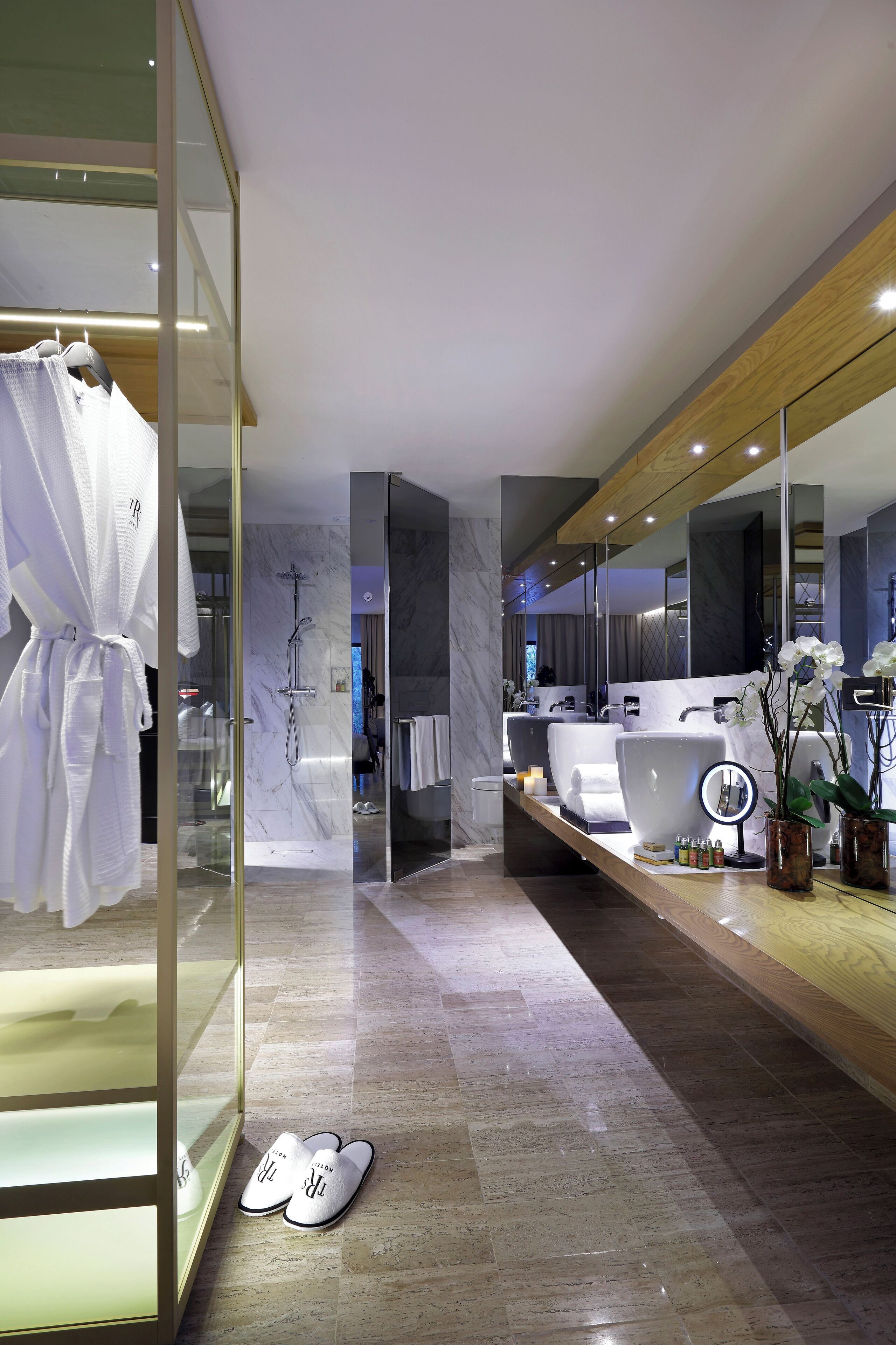 A modern bathroom with a glass shower enclosure, a large mirror, and a vanity with a sink and towel rack.