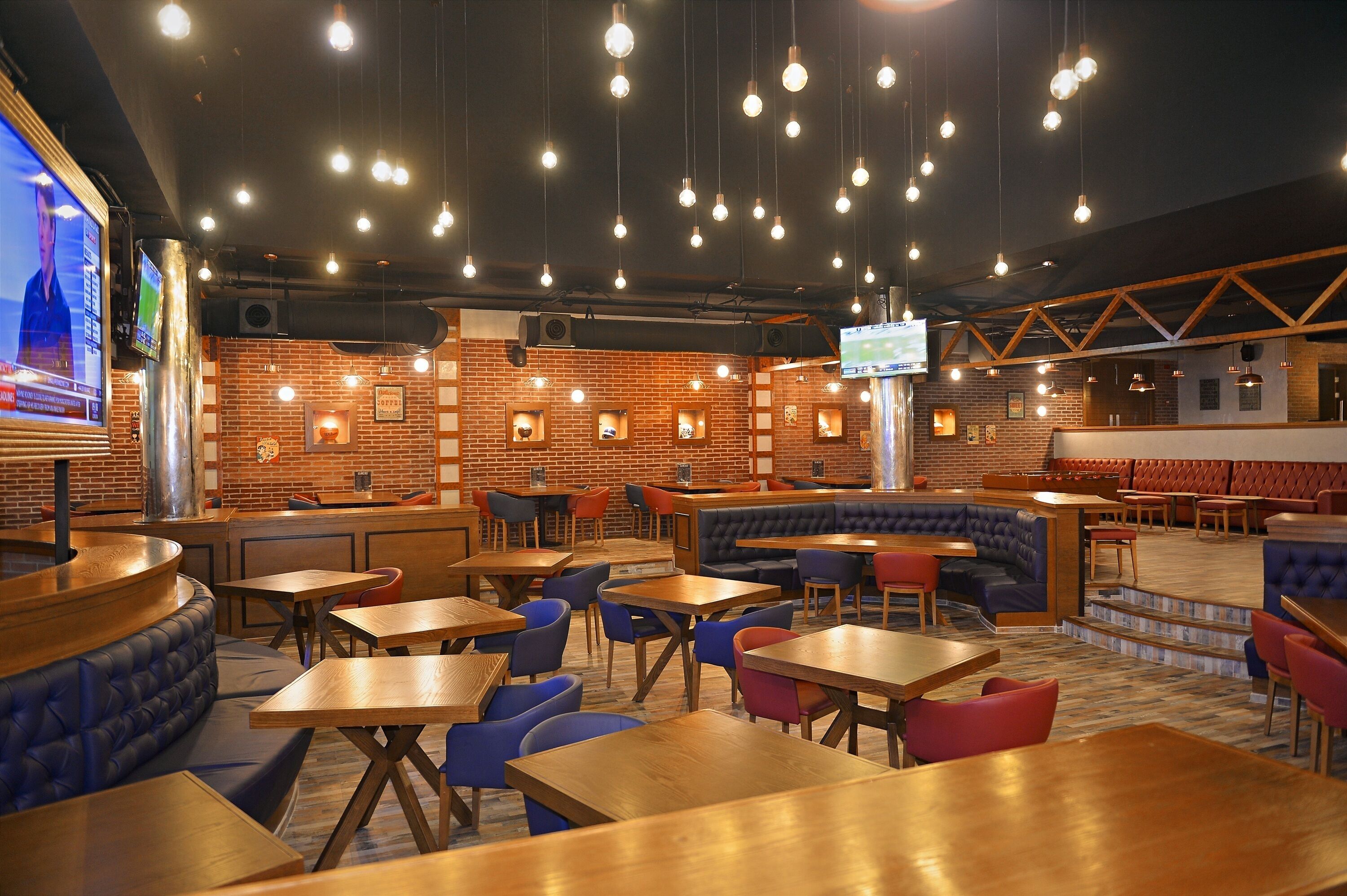 A restaurant with brick walls, hanging light bulbs, and multiple seating areas including booths and tables.