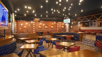A restaurant with brick walls, hanging light bulbs, and multiple seating areas including booths and tables.