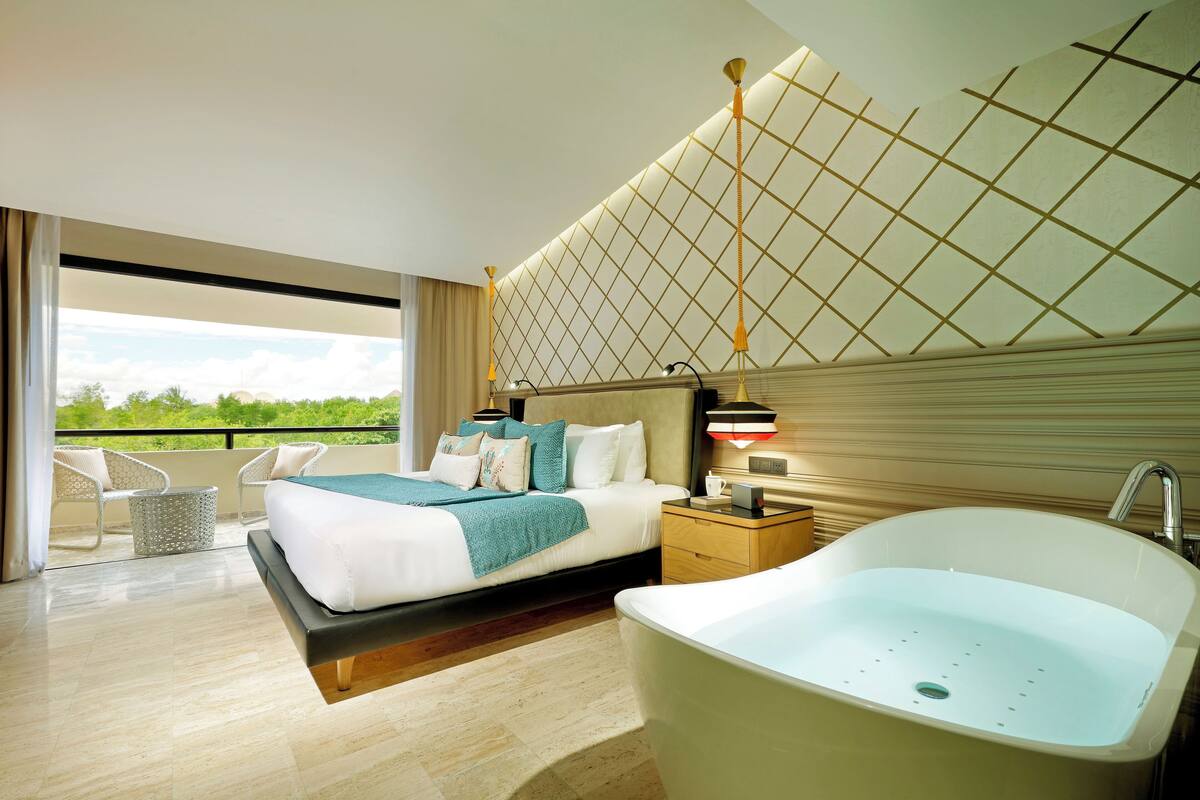 Habitació d'hotel moderna amb un llit gran, una banyera i un balcó amb vistes.