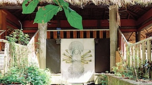 A traditional thatched-roof structure with a central water feature and stone steps leading to a tiled entrance.