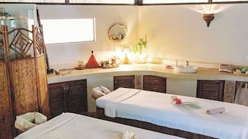 Una habitación con dos camas, ventilador de techo, ventana y espejo.