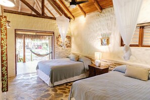 A room with two beds, a hammock, a stone floor, and a thatched door. - Natura Cabana Boutique Hotel & Spa (Cabarete)
