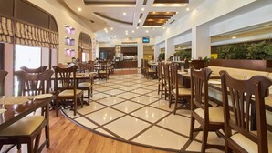 A spacious restaurant with wooden tables and chairs, a tiled floor, and a modern ceiling design. - Fortune Park Panchwati, Kolkata - Member ITC Hotels' Group (Howrah)