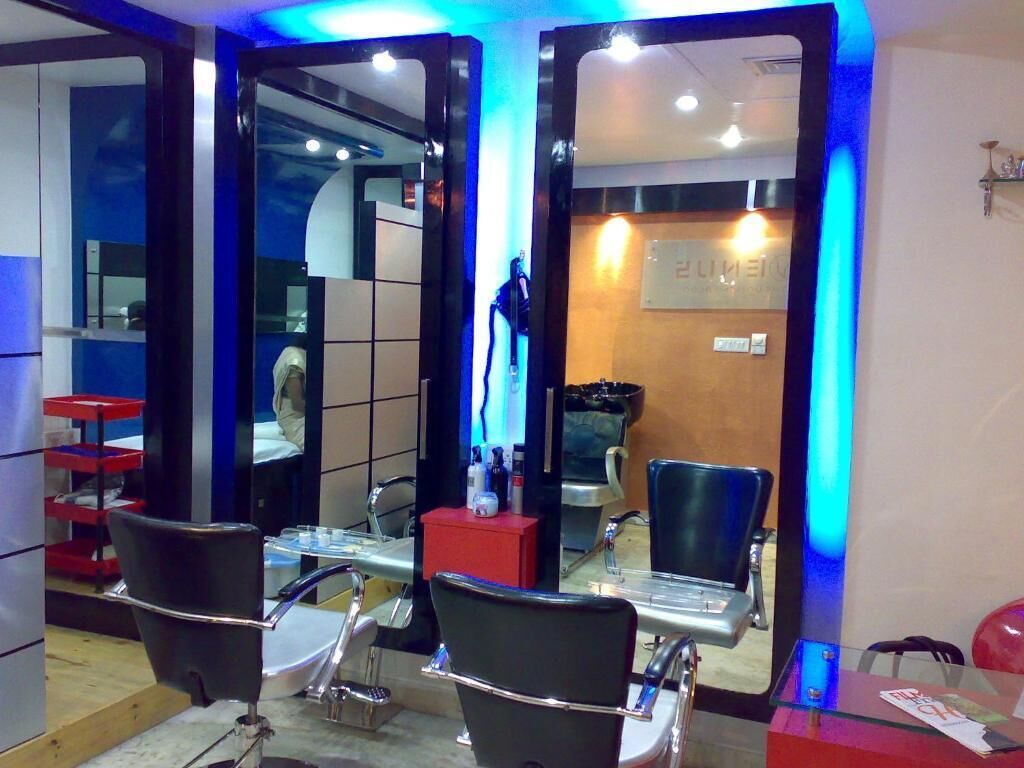 Un salón con espejos, sillas y una barra.