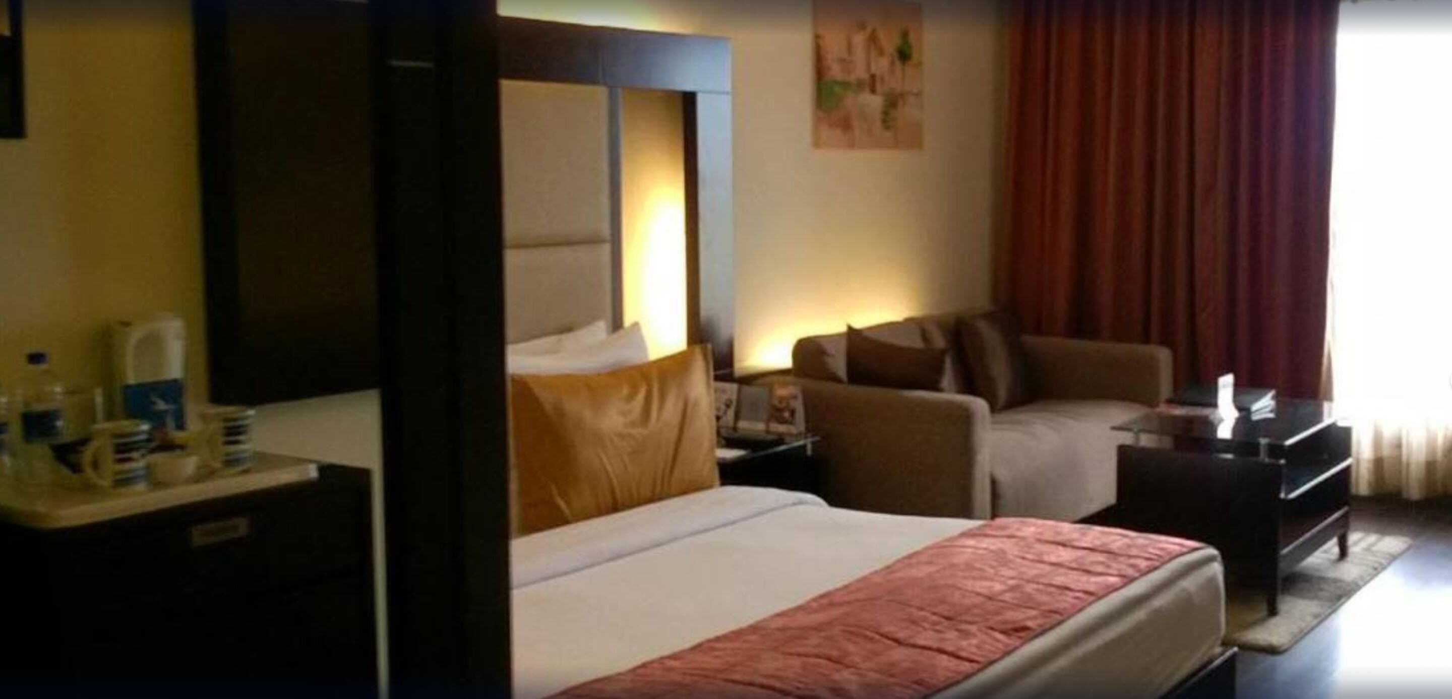 Une chambre d’hôtel avec un lit, un canapé, un bureau avec une lampe et un piano.