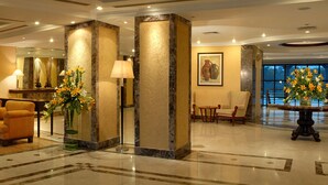 A lobby with a sofa, armchairs, a coffee table, a reception desk, and a large vase of flowers. - Fortune Park Panchwati, Kolkata - Member ITC Hotels' Group (Howrah)