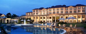 A hotel with a large pool, outdoor seating, and a fountain.