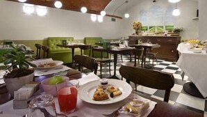 A dining area with green upholstered chairs, a checkered floor, and a view of the outdoors through large windows. - Graziella Patio Hotel (Arezzo)