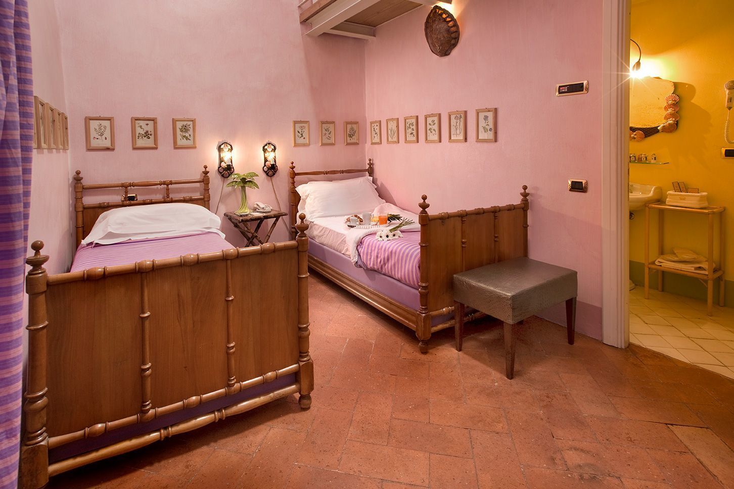 A bedroom with two wooden beds, a bench, and a bathroom visible through an open door.
