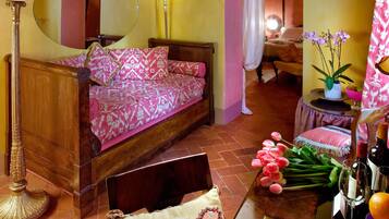 A cozy bedroom with a wooden bed, a mirror, a floor lamp, and a small table with a vase of flowers.